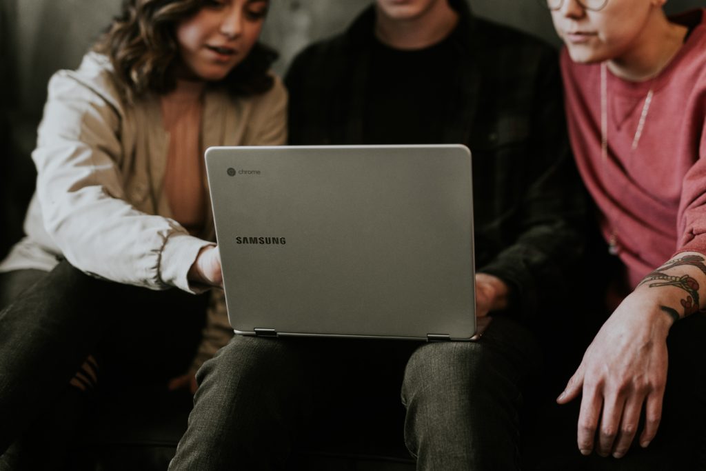Three young people using a laptop